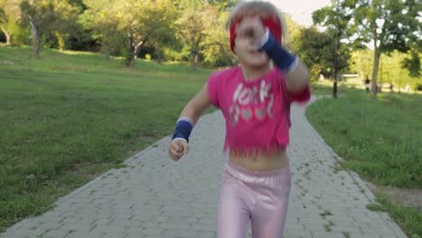 little caucasian runner child girl in pink sportswear running outdoors in park. workout for kids