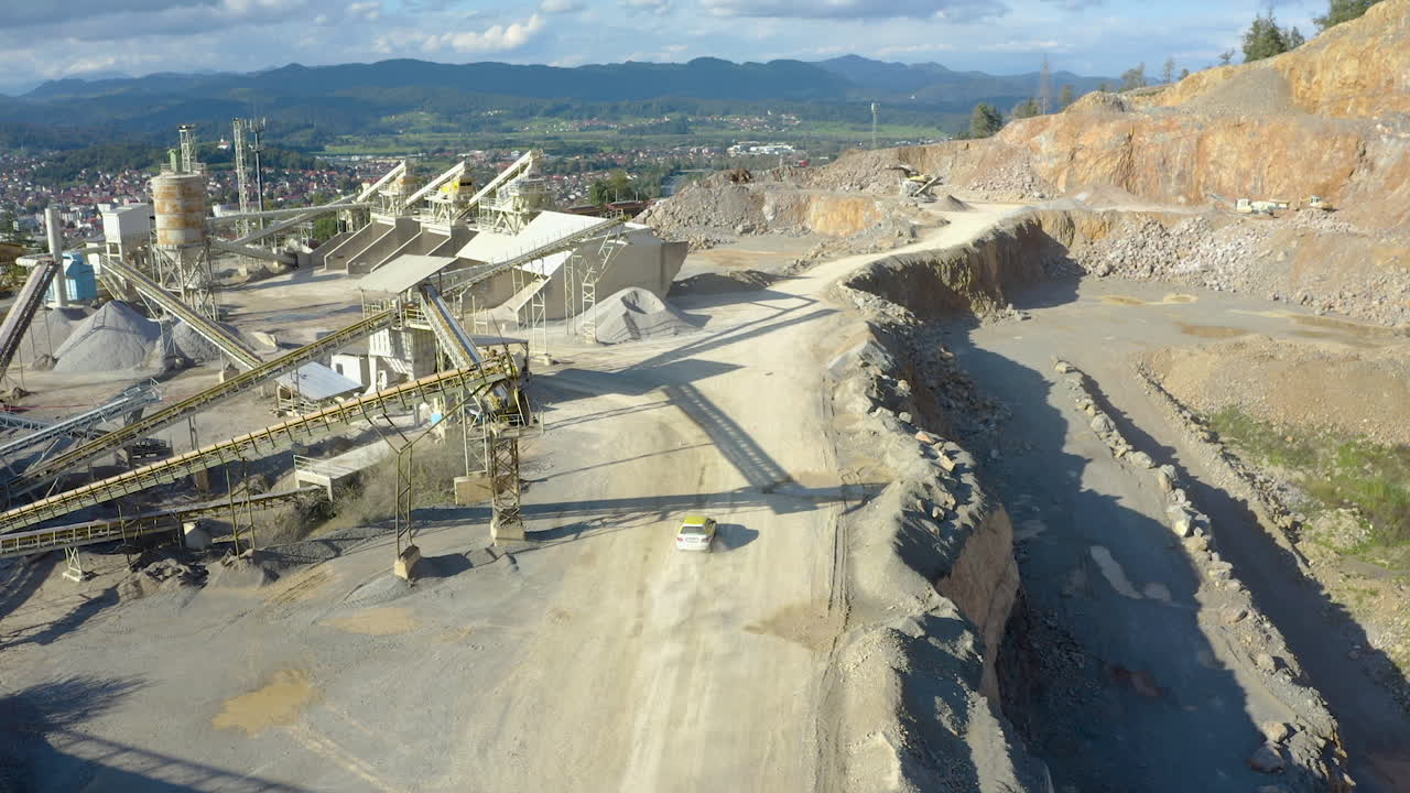 Drone flying over quarry with rally car driving by