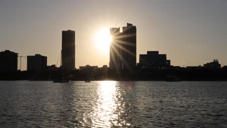 el sol se pone detrás del horizonte urbano, los barcos en el agua