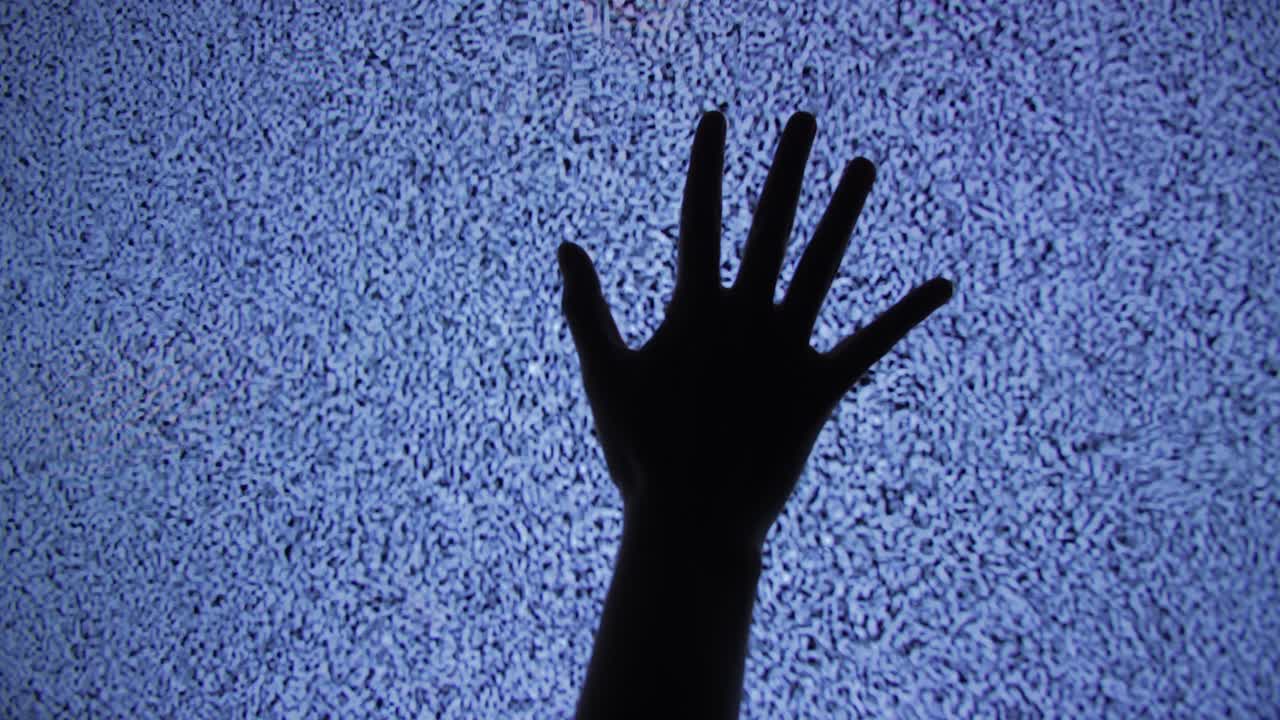 Silhouette di una mano umana contro il rumore statico della televisione