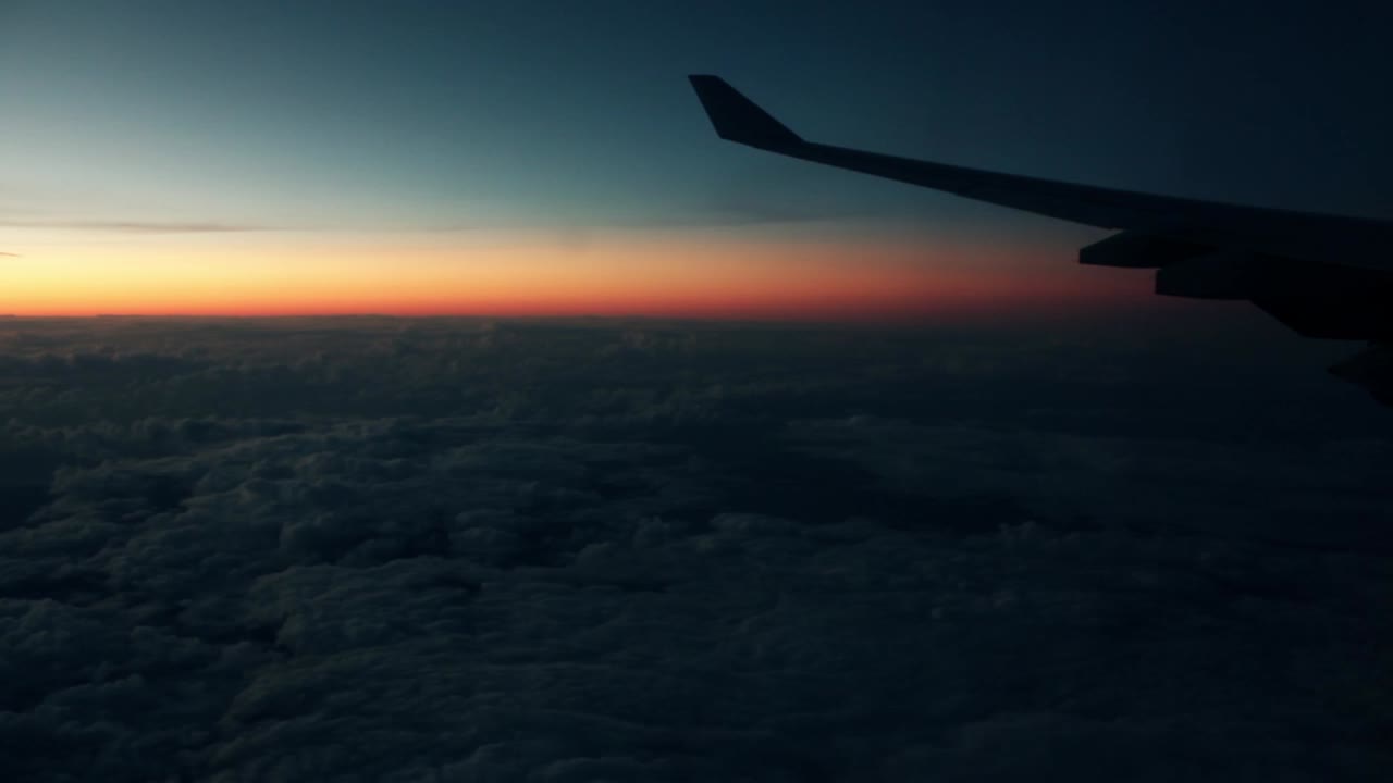 Aile d'avion au-dessus des nuages lors d'un vol au coucher du soleil