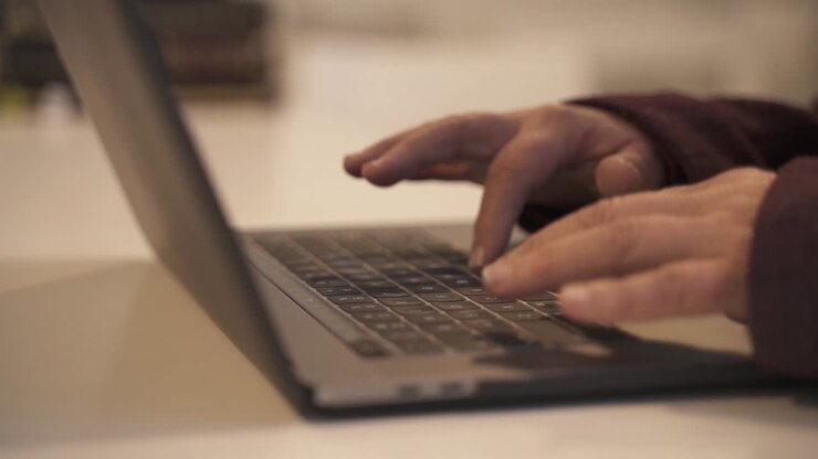 Nahaufnahme älterer weiblicher Hände, die langsam am Laptop im Büro tippen, Zeitlupe