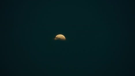 the slow disappearance of a lunar eclipse in black darkness behind a horizon with clouds. a total lunar eclipse occurred on 26 may 2021.