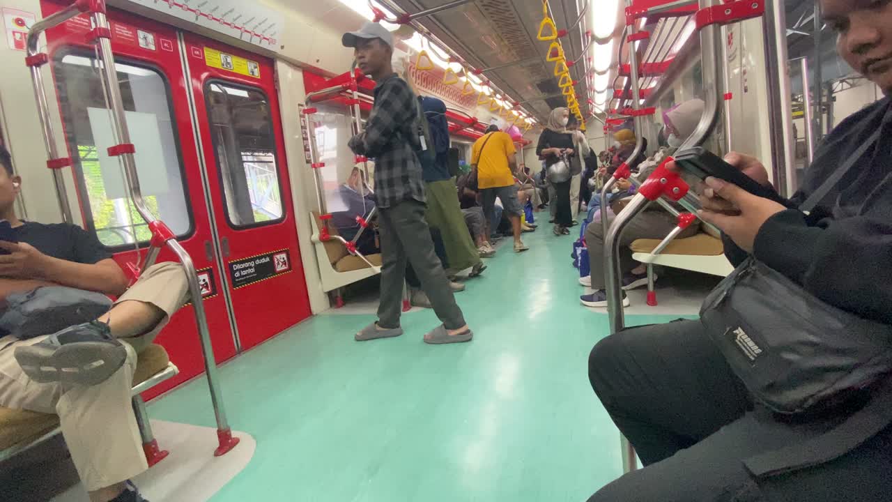 Passengers enter through the door, looking for empty seats in the electric train carriage.