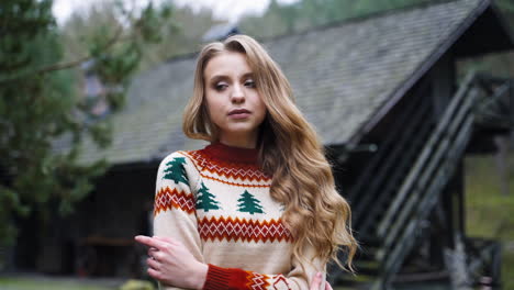 attractive girl outdoors. beautiful young woman in knitted christmas sweater standing alone in the village in cold autumn season.