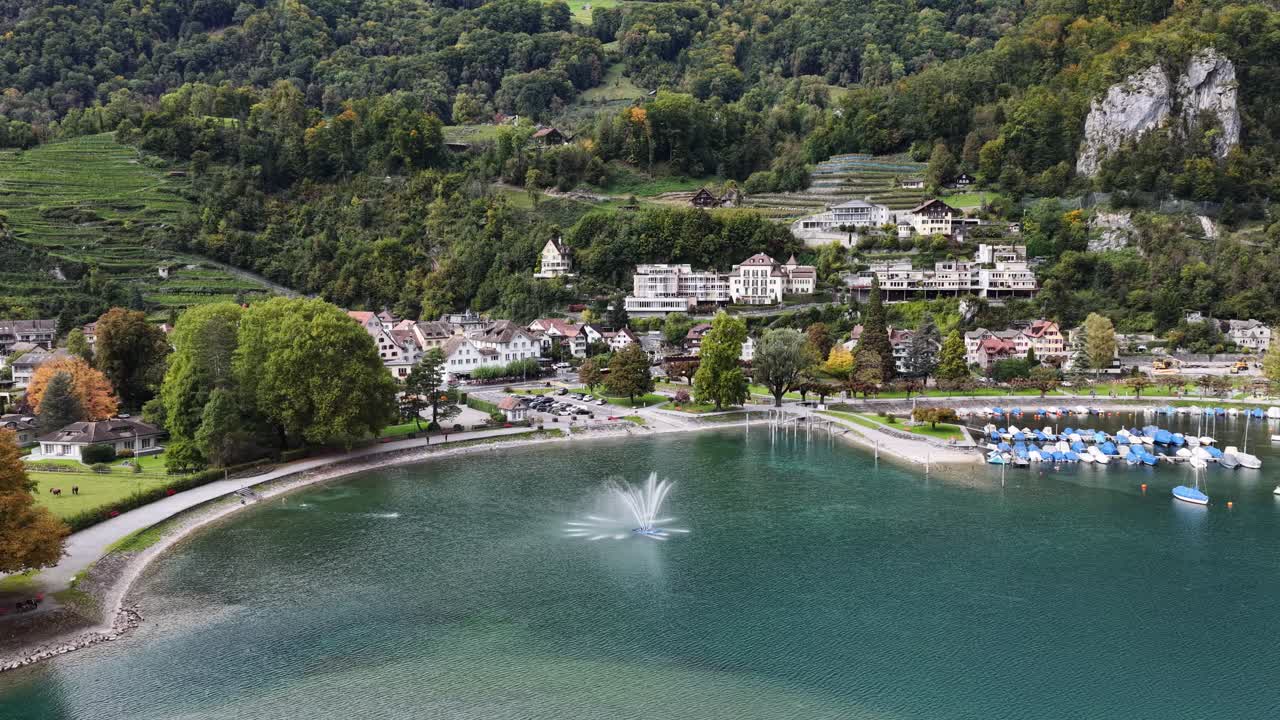 The town of Walenstadt, Schweiz, sits on the terraced hills overlooking Walensee, where a fountain jets water in the harbor. Concept of harmony of civilization and Alpine nature
