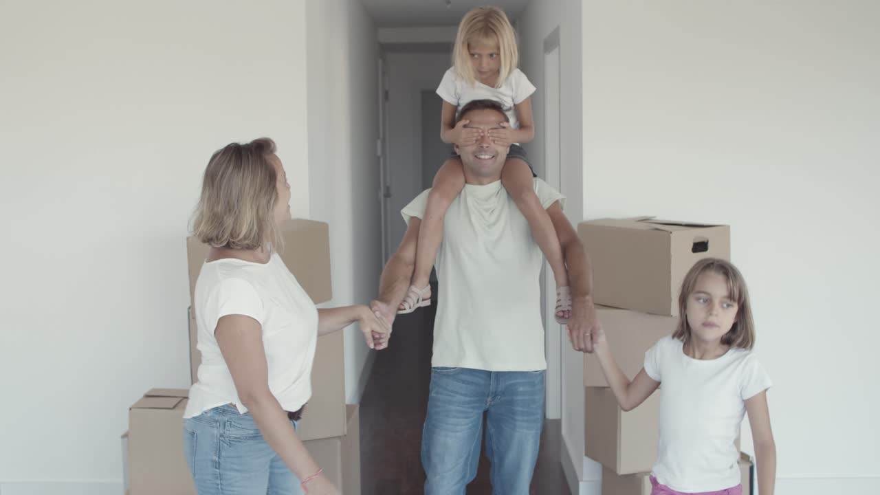 Dos niñas felices y su mamá guiando a papá con los ojos cerrados