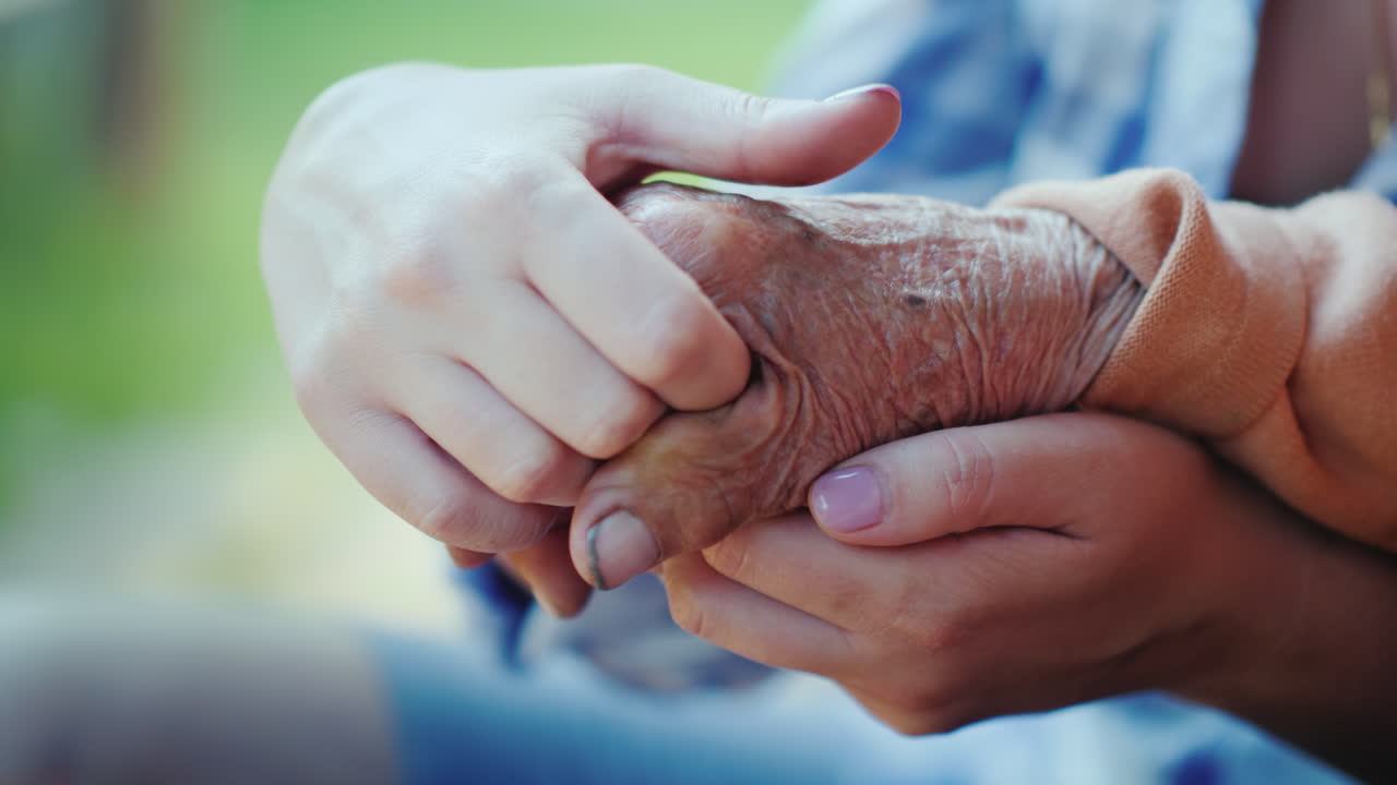 una mujer joven sostiene un video de primer plano de la mano de una anciana
