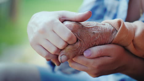 a young woman holds an elderly lady's hand close-up video