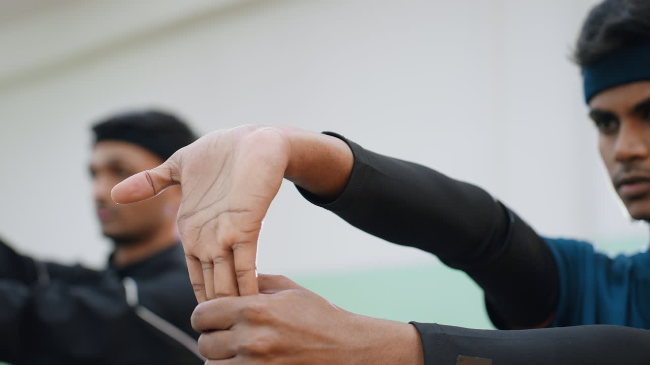 Close up of athletes stretching hands during indoor workout session focusing on wrist flexibility, control, and preparation for sports activity with blurred training background