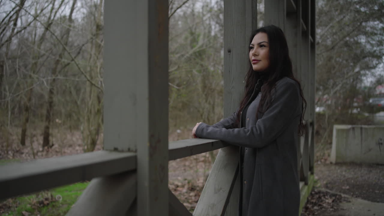 Mulher contemplativa aprecia a natureza na ponte, vira-se para sorrir para a câmera