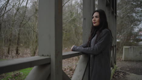 contemplative woman enjoys nature on bridge, turns to smile at the camera