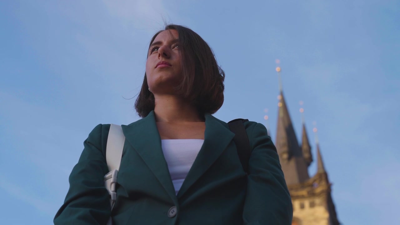 Primo piano con inquadratura dal basso di una donna con campanili di chiesa sullo sfondo, Praga.