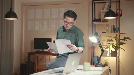 creative designer sits on his desk works on a storyboard, looks at his sketches and concepts, choosing the best drawings for his project, comics compilation, application ui or game plot