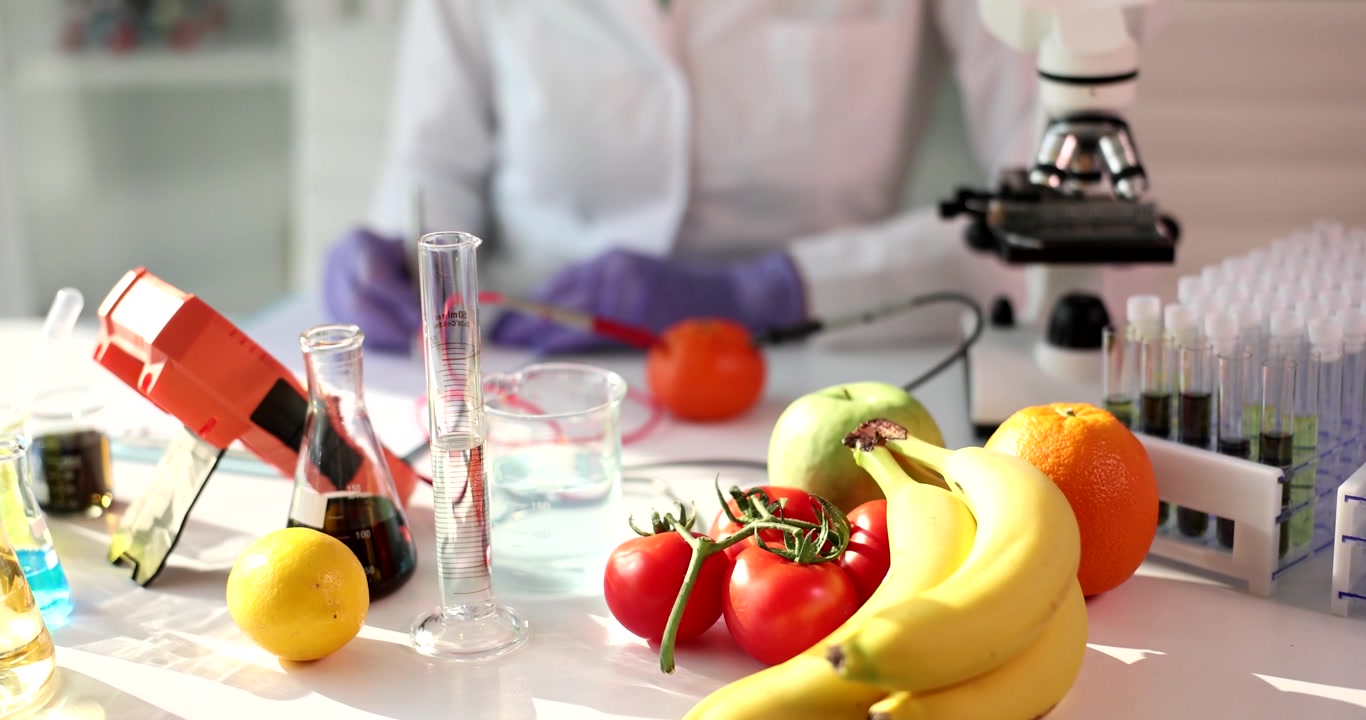 Frutas frescas e vidraria de laboratório sobre a mesa para estudo de nutrição