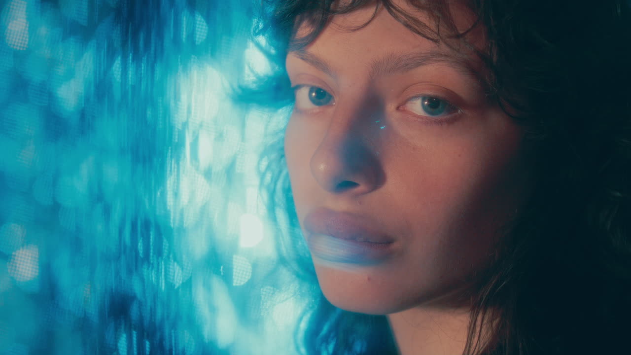 Portrait of Young Beautiful Woman against Blue Bokeh Background