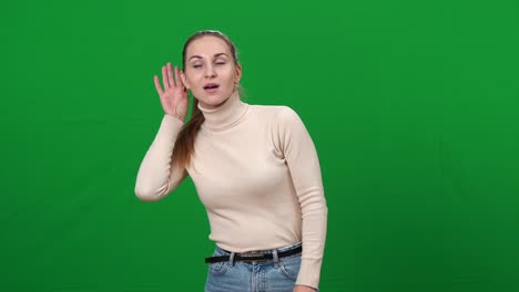 bonita mujer caucásica morena escuchando algo sosteniendo la mano en la oreja y sacudiendo la cabeza sí. retrato de una dama escuchando en el fondo de la pantalla verde chromakey. feminidad y concepto de chismes