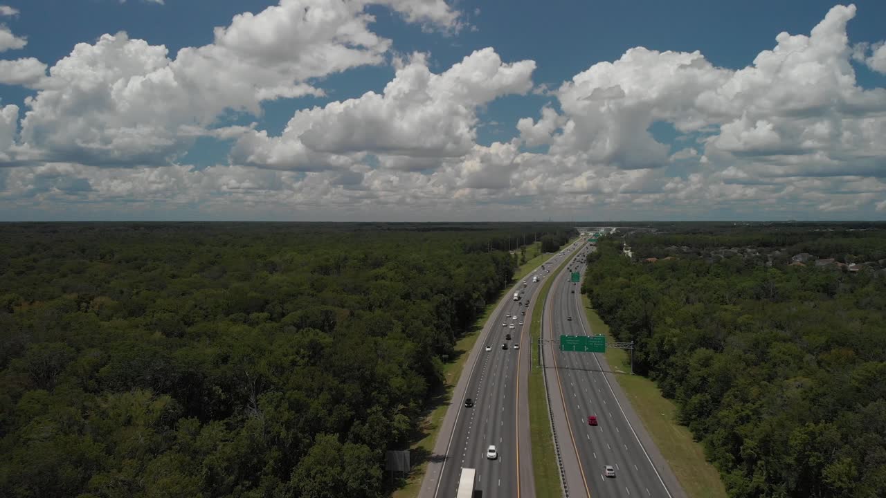 drone panorámica aérea disparado revelando la carretera y las carreteras coches que pasan por el cielo azul nubes blancas árboles en el lado de la carretera