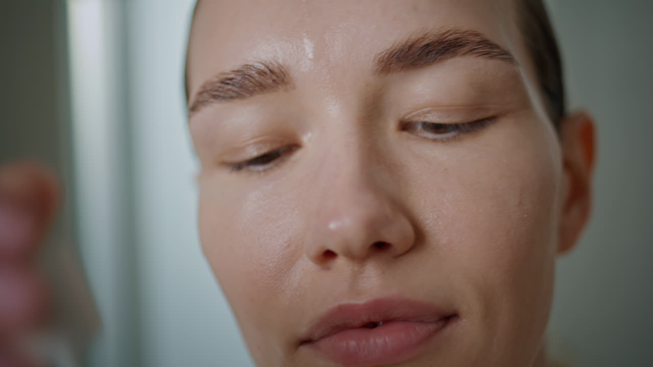 Woman dropping skincare liquid on face closeup. Girl applying nourishing serum