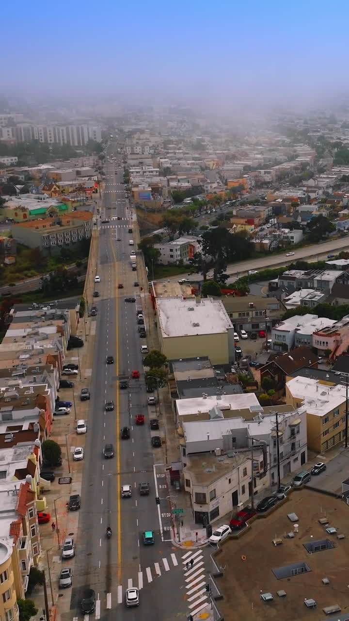 Lively traffic on the roads of beautiful city. San Francisco panorama getting lost in the thick fog at daytime. Aerial perspective. Vertical video