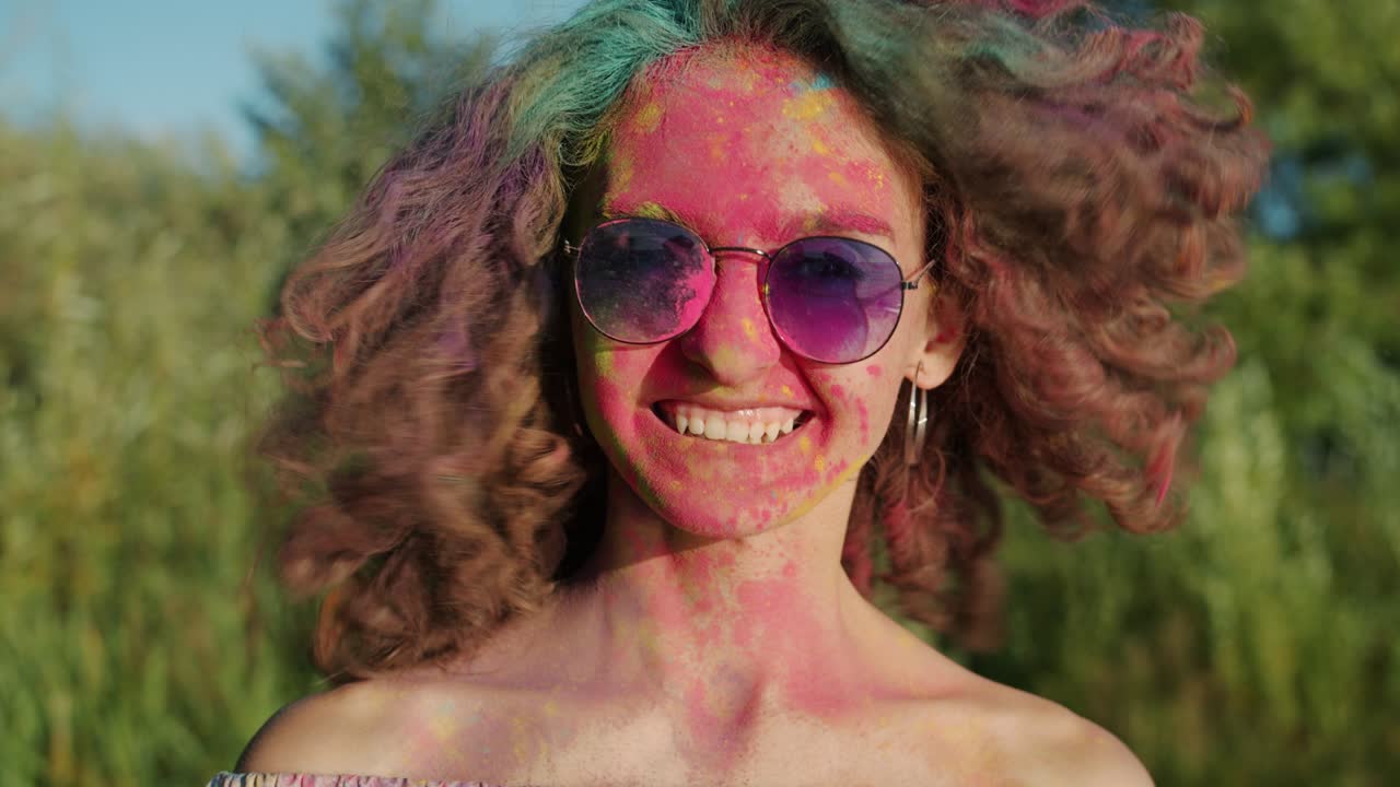 Rallentatore di una bella ragazza che agita i capelli coperti di polvere gulal al festival Holi