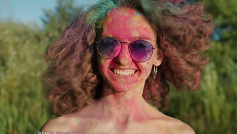 slow motion of beautiful girl waving hair covered with gulal paint at holi festival