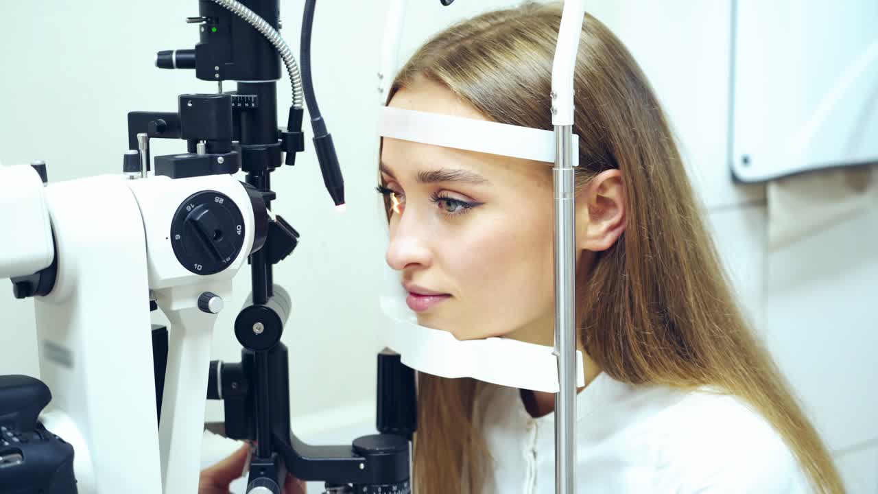 Young woman checking her eyes in clinic. Biomicroscopy device. Doctor examining eye structure of a female patient with the help of modern medical equipment. Professional health care.