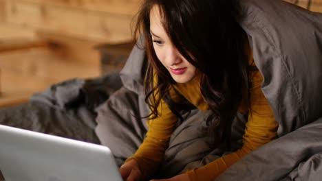 Woman-using-laptop-on-bed