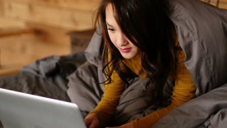 woman using laptop on bed