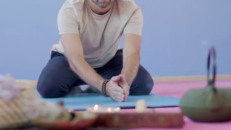 hombre sentado en el suelo y practicando yoga con incienso