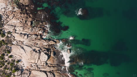 Vista-De-Arriba-Hacia-Abajo-De-La-Costa-Rocosa-En-La-Playa-De-Llandudno,-Ciudad-Del-Cabo,-Sudáfrica---Toma-Aérea-De-Drones