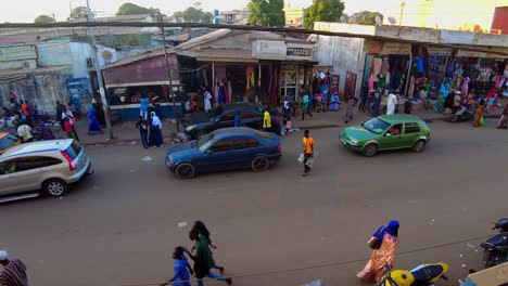 colorful street market high top panning view of african serekunda market street people stores and cars passing by