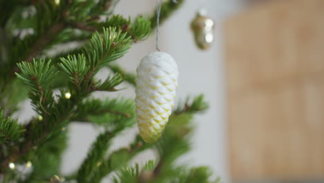 beautiful white ornament hanging on christmas tree surrounded by vibrant green pine branches and warm glowing lights, cozy festive holiday setting captured with soft background