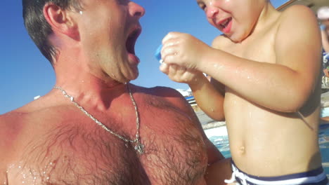 padre e hijo jugando en la piscina al aire libre