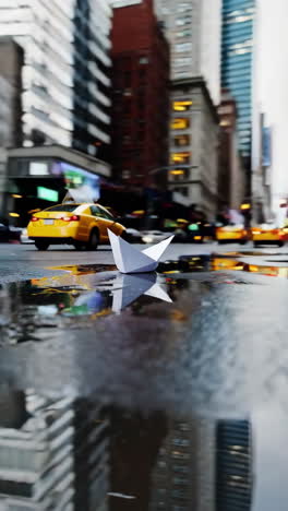 paper boat in a puddle on a city street