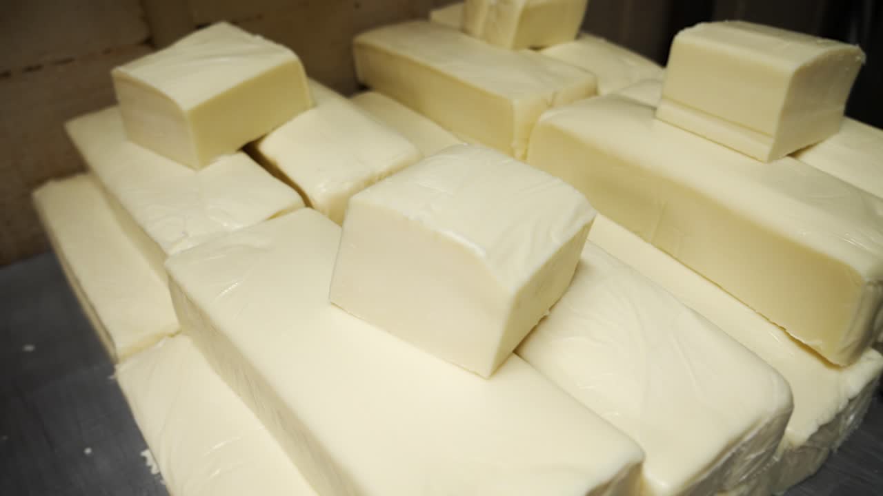Blocks of commercial fresh white cheese stacked in warehouse, slow motion slider 4K
