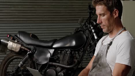 mecánico masculino usando una computadora portátil en un garaje de reparación de motocicletas 4k