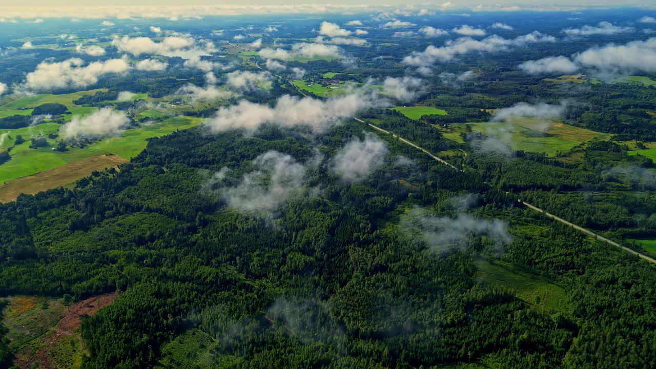 High altitude aerial view of a rural, forested countryside on a partly cloudy day