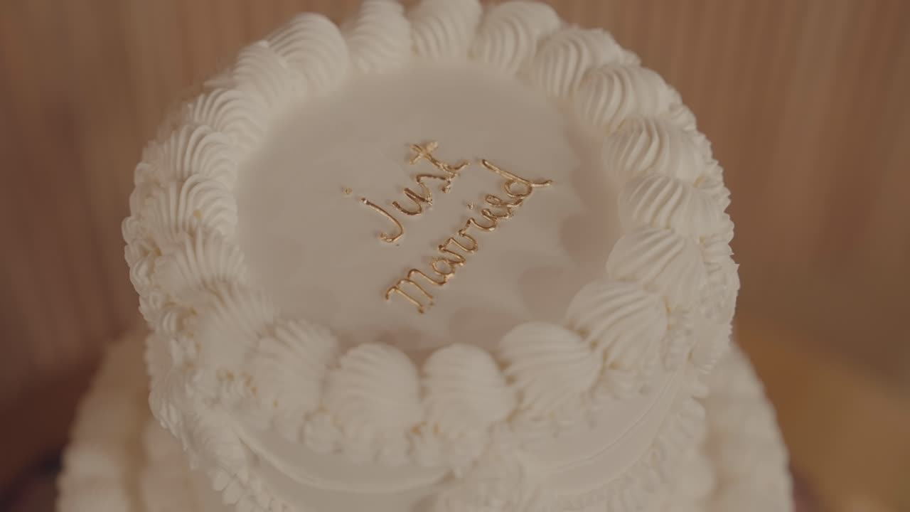 white frosted wedding cake with “Just Married” written in gold icing