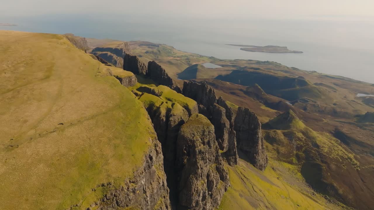 Aerial drone footage of the dramatic mountain landscapes on the Isle of Skye, Scotland. Sweeping panoramic views of majestic peaks, green valleys, and wild nature. Quiraing walk