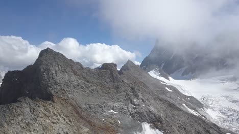 toma aérea en los alpes suizos descubriendo una cordillera salvaje en las nubes