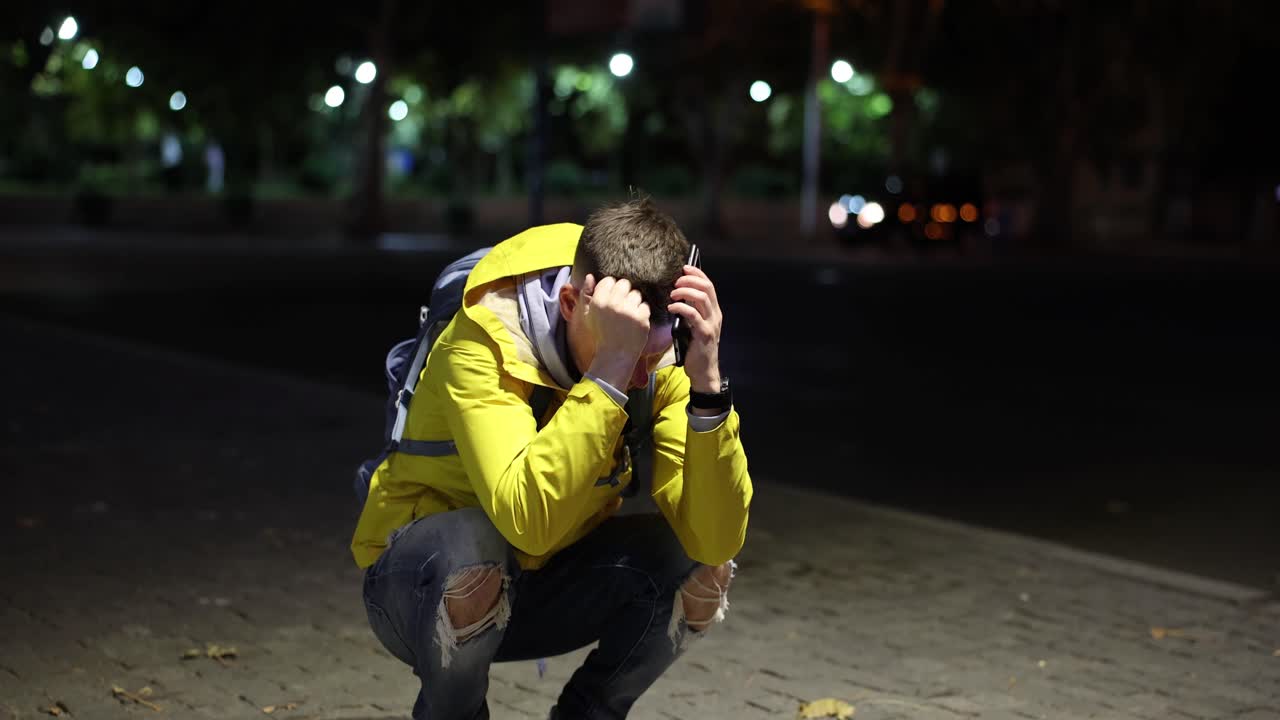 Distressed man looking at phone at night on a city street