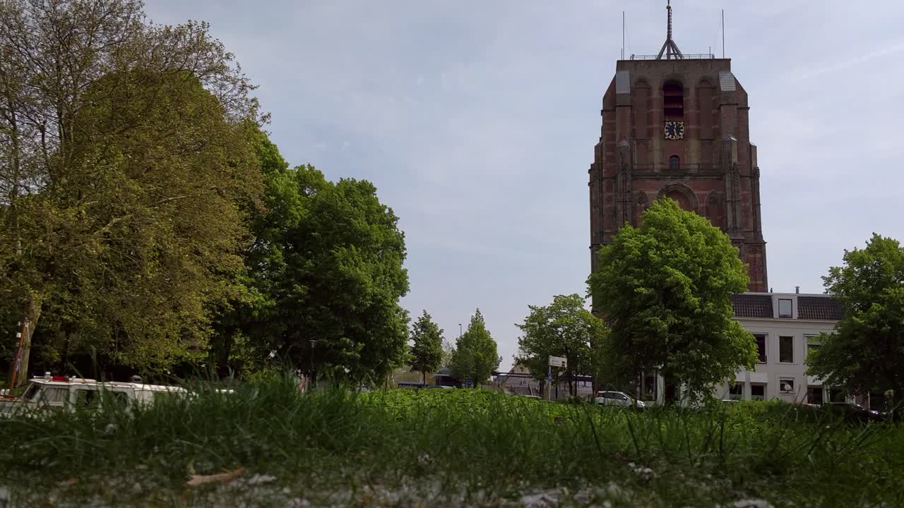 antigua torre de la iglesia oldehove leeuwarden fast dolly shot frente al río ee con botes amarrados en el parque