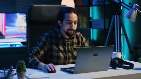 Freelancer-in-neon-lit-home-office-sitting-at-desk-and-typing-on-laptop-keyboard