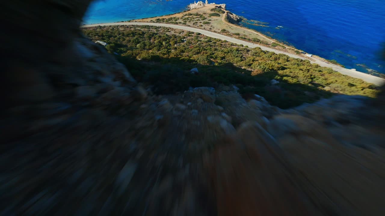 Volo dinamico di drone FPV in discesa tra le montagne verdi verso il mare blu nella valle