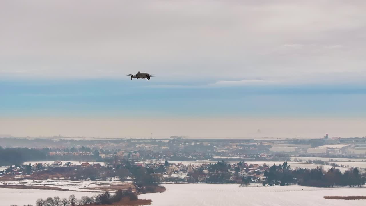 Drone flying over snowy winter landscape and distant cityscape, Czechia