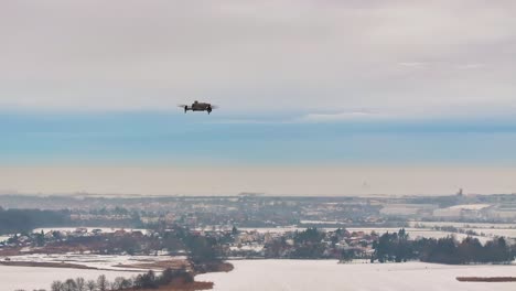 Drone flying over snowy winter landscape and distant cityscape, Czechia