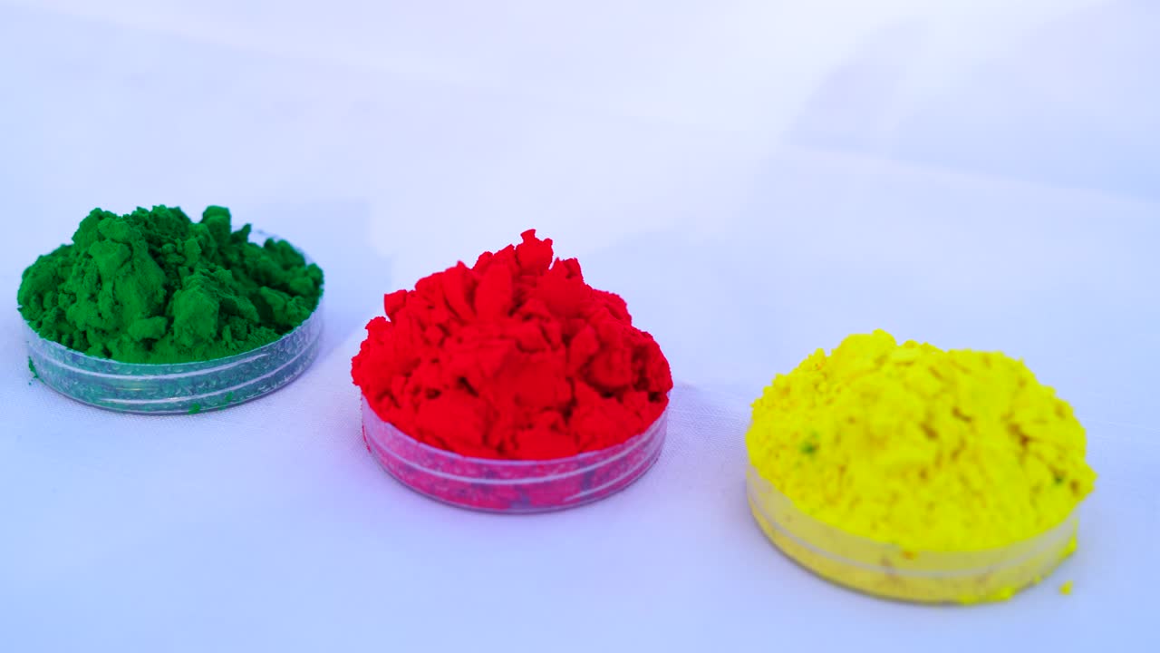 녹색, 빨간색 및 노란색 gulali 색 파우더는 홀리 축제를 위해 바닥에 들고 있습니다.