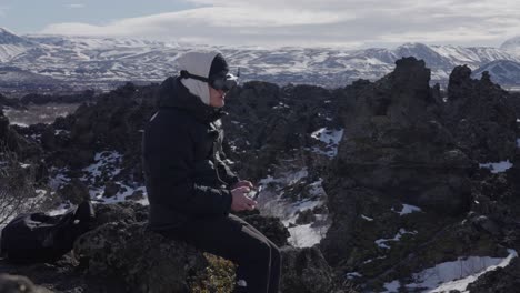 Man-fly-FPV-drone-using-goggles-around-scenic-volcanic-landscape,-Iceland