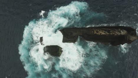 aerial view of the ocean swelling against a rocky outcrop